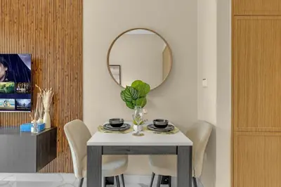 a dining room with a table and a mirror at Fully-Equipped Studio with Pool, Gym & Chic Location in Dubai