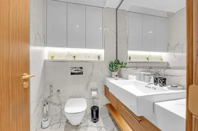 a white bathroom with a toilet and a sink at Fully-Equipped Studio with Pool, Gym & Chic Location in Dubai