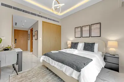 a bedroom with a large bed and a desk in it at Fully-Equipped Studio with Pool, Gym & Chic Location in Dubai
