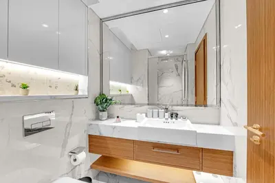 a white bathroom with a sink and a mirror at Fully-Equipped Studio with Pool, Gym & Chic Location in Dubai