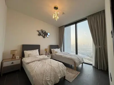 a bedroom with two beds and a large window at The Crest Sobha Hartland in Dubai