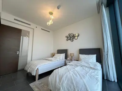 a bedroom with two beds and a clock on the wall at The Crest Sobha Hartland in Dubai