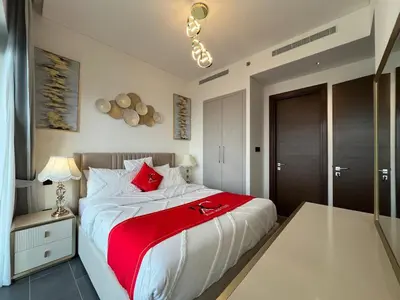 a bedroom with a large white bed with red pillows at The Crest Sobha Hartland in Dubai