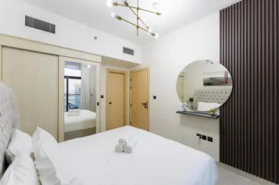 a bedroom with a white bed and a mirror at Cosy 2 Bed Apartment in Al Jaddaf in Dubai