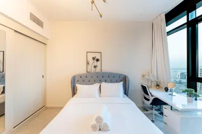 a bedroom with a bed with a desk and a window at Cosy 2 Bed Apartment in Al Jaddaf in Dubai