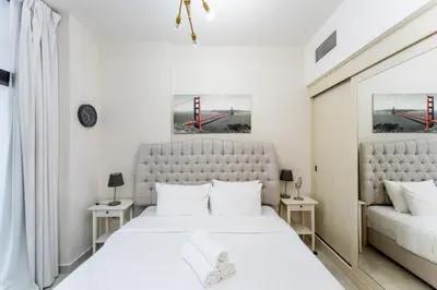 a white bedroom with a large bed and two tables at Cosy 2 Bed Apartment in Al Jaddaf in Dubai