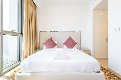 a bedroom with a large white bed with pink pillows at Superhost- Elegant Downtown 3BR , Burj Khalifa View in Dubai