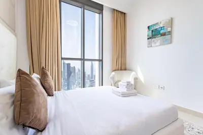 a bedroom with a white bed with a large window at Superhost- Elegant Downtown 3BR , Burj Khalifa View in Dubai