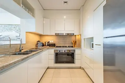 a kitchen with white cabinets and a sink at Superhost- Elegant Downtown 3BR , Burj Khalifa View in Dubai