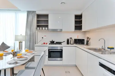 a kitchen with white cabinets and a table with chairs at Executive 2-Bedroom Apartment in Downtown views 2 with access to Dubai mall in Dubai