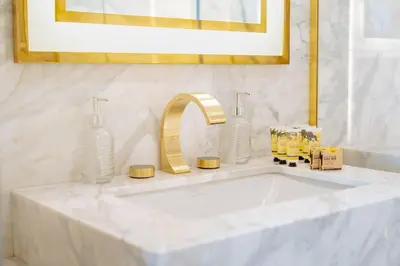 a white bathroom sink with a gold faucet at PVH - Emaar Residence Fashion Avenue - Burj Khalifa View Studio in Dubai