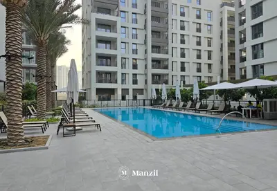 a swimming pool with chairs and umbrellas next to a building at Waterfront 1BR Apartment in Creek Harbour near Downtown in Dubai