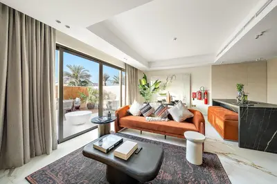 a living room with an orange couch and a large window at FIRST CLASS VILLA Hidden Luxury Gem in Dubai