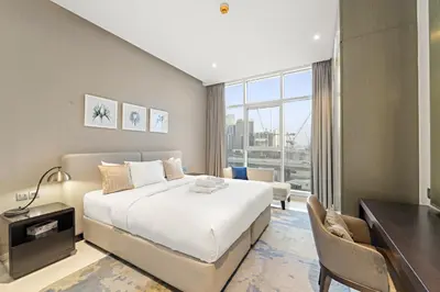 a bedroom with a bed and a desk and a window at Spacious 1BR with Balcony and Pool Access in Dubai