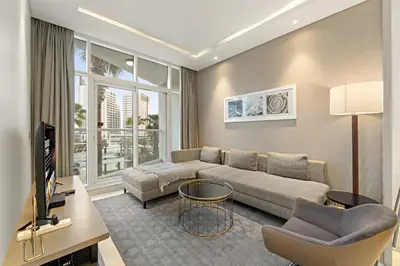 a living room with a couch and a tv at Spacious 1BR with Balcony and Pool Access in Dubai