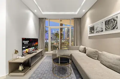 a living room with a couch and a flat screen tv at Spacious 1BR with Balcony and Pool Access in Dubai