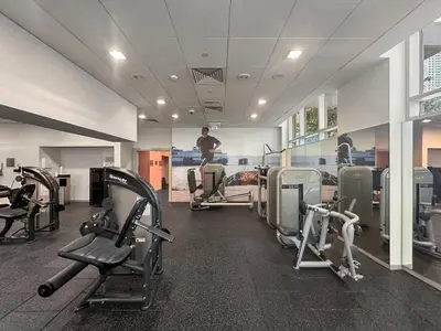 a gym with cardio equipment and a man in the background at FIRST CLASS 2BR Luxe & Lively Living in Dubai