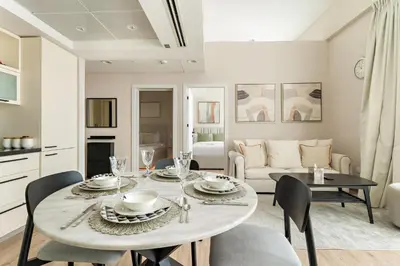 a kitchen and living room with a table and chairs at FIRST CLASS 2BR Luxe & Lively Living in Dubai