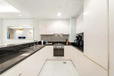 a white kitchen with black and white appliances at Luxe 2BR at Paramount l High Floor with Infinity Pool in Dubai