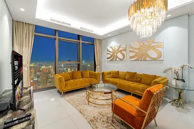 a living room with yellow furniture and a large window at Luxe 2BR at Paramount l High Floor with Infinity Pool in Dubai