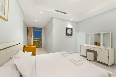 a white bedroom with a large bed and a desk at Luxe 2BR at Paramount l High Floor with Infinity Pool in Dubai