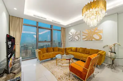 a living room with yellow couches and a chandelier at Luxe 2BR at Paramount l High Floor with Infinity Pool in Dubai