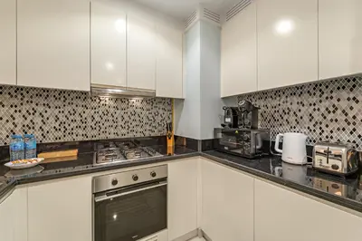 a kitchen with white cabinets and a stove top oven at Luxe 2BR at Paramount l High Floor with Infinity Pool in Dubai