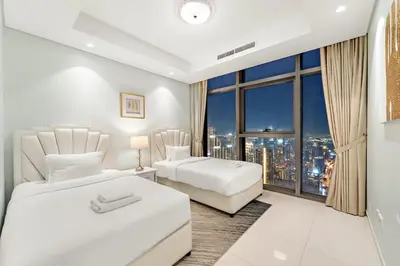 a bedroom with two beds and a large window at Luxe 2BR at Paramount l High Floor with Infinity Pool in Dubai