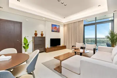 a living room with a white couch and a table at Samaya Holiday Homes - Modern Luxe Apartments - Nobles Tower in Dubai