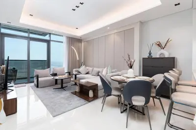 a living room with a couch and a table and chairs at Samaya Holiday Homes - Modern Luxe Apartments - Nobles Tower in Dubai