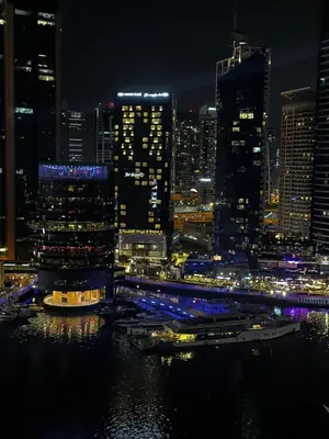 a city skyline at night with boats in the water at Modern 1BR Apt With Access to Jacuzzi, Sauna & Pool in Dubai