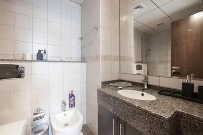 a bathroom with a sink and a toilet and a mirror at Modern 1BR Apt With Access to Jacuzzi, Sauna & Pool in Dubai