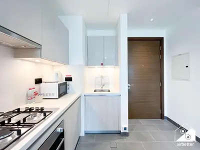 a white kitchen with a stove and a sink at Luxury 1-Bed in Meydan with Balcony & City Views in Dubai