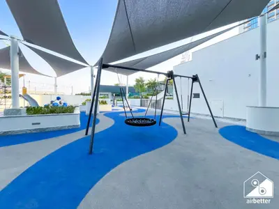 a swing set in a playground with blue carpet at Modern 1B Luxury , Scenic City Balcony, Pool & Gym in Dubai
