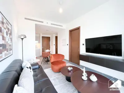 a living room with a couch and a tv at Modern 1B Luxury , Scenic City Balcony, Pool & Gym in Dubai