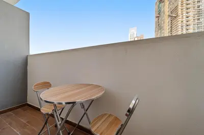 a table and three stools sitting on a balcony at Golden Woods Escape Near Marina & JBR in Dubai