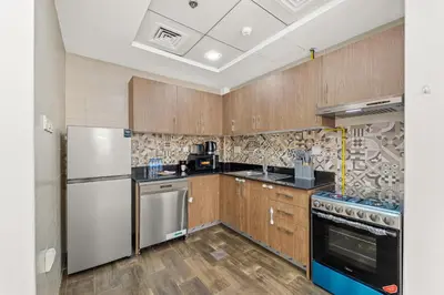 a kitchen with wooden cabinets and stainless steel appliances at Golden Woods Escape Near Marina & JBR in Dubai