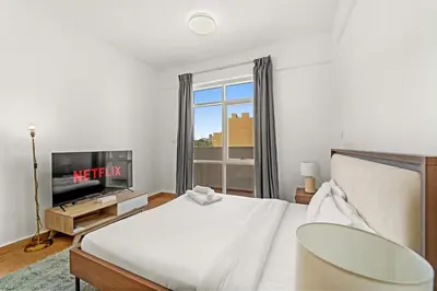 a bedroom with a bed and a tv and a window at Golden Woods Escape Near Marina & JBR in Dubai
