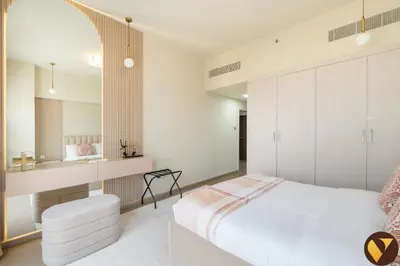 a bedroom with a white bed and a white chair at Vogue Jeewar JVC near Circle Mall, One Bedroom Apartment with Balcony and Park view, Access to all Amenities in Dubai