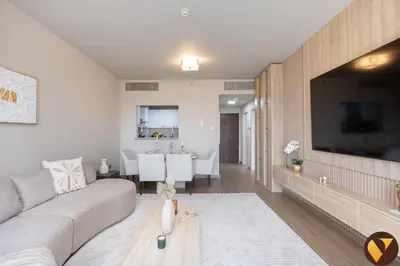 a living room with a couch and a dining room at Vogue Jeewar JVC near Circle Mall, One Bedroom Apartment with Balcony and Park view, Access to all Amenities in Dubai