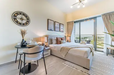 a bedroom with a bed and a table and a clock at Close to Meydan Racecourse and Ras Al Khor Wildlife Sanctuary, And a Quick Drive to Downtown Dubai and the Iconic Burj Khalifa - Azizi Riviera 44, Meydan by Deluxe Holiday Homes in Dubai