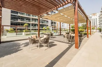 a patio with tables and chairs on a building at Close to Meydan Racecourse and Ras Al Khor Wildlife Sanctuary, And a Quick Drive to Downtown Dubai and the Iconic Burj Khalifa - Azizi Riviera 44, Meydan by Deluxe Holiday Homes in Dubai