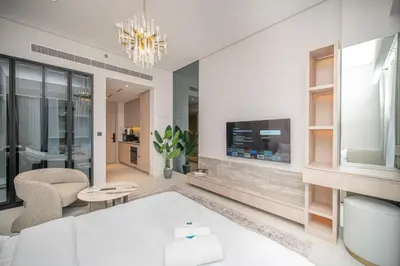a living room with a chandelier and a tv at Modern Studio Apartment for Rent Fully Furnished in Dubai