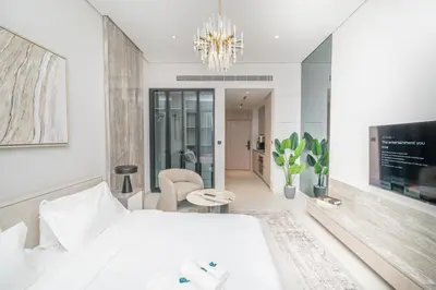 a bedroom with a white bed and a chandelier at Modern Studio Apartment for Rent Fully Furnished in Dubai