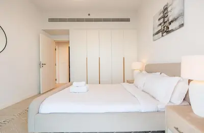 a white bedroom with a large bed with white pillows at Magical La Vie JBR Apt with Private Beach Access in Dubai