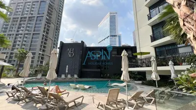 a swimming pool with chairs and umbrellas in front of a building at Aspin Modern Studio Apartment in AHAD Residency in Dubai