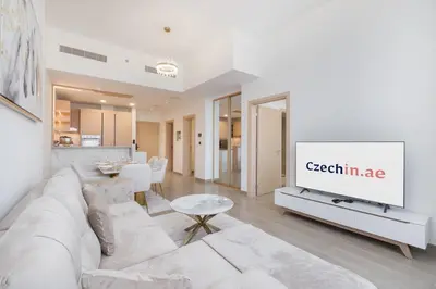 a living room with a white couch and a tv at Modern Aura Living Chic 1BR Hideaway in JVC in Dubai