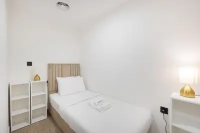 a white bedroom with two beds and a lamp at Modern Aura Living Chic 1BR Hideaway in JVC in Dubai