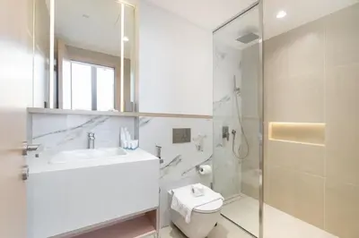 a bathroom with a toilet and a sink and a shower at Modern Aura Living Chic 1BR Hideaway in JVC in Dubai