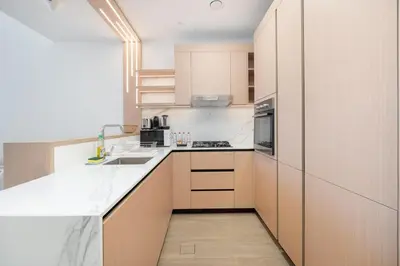 a kitchen with white counter tops and wooden cabinets at Modern Aura Living Chic 1BR Hideaway in JVC in Dubai